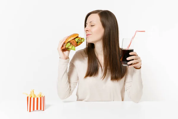 Boldog fun fiatal nő ül asztal, hamburger, sült krumpli, cola üvegben elszigetelt fehér background. Megfelelő táplálkozás, vagy a klasszikus amerikai gyorsétterem. Hirdetés terület másol hely. — Stock Fotó
