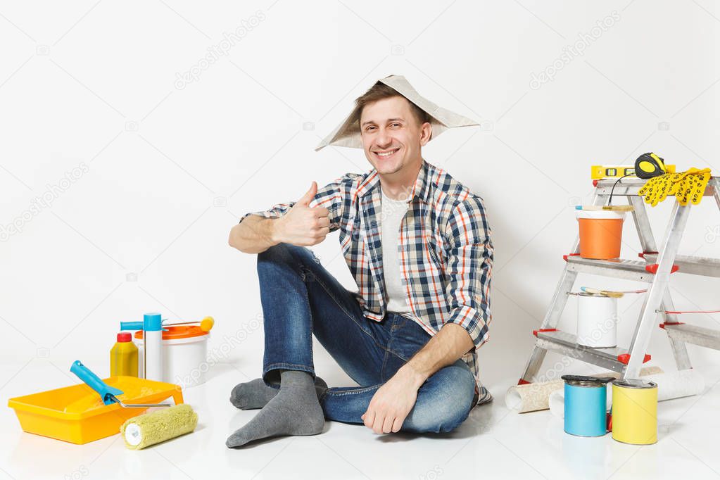 Fun happy smiling man in newspaper hat sitting on floor with ins