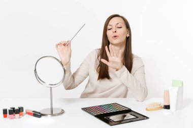 Çekici kadın tırnak düzeltme kullanarak tırnak ile beyaz arka plan üzerinde izole set yüz Dekoratif kozmetik makyaj uygulamak masada oturan, başarısız. Güzellik kadın moda yaşam tarzı kavramı.