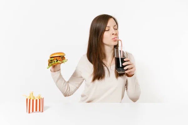 Mulher beber cola de garrafa de vidro de palha, sentado à mesa com hambúrguer, batatas fritas isoladas em fundo branco. Nutrição adequada ou fast food clássico americano. Área de publicidade com espaço de cópia . — Fotografia de Stock