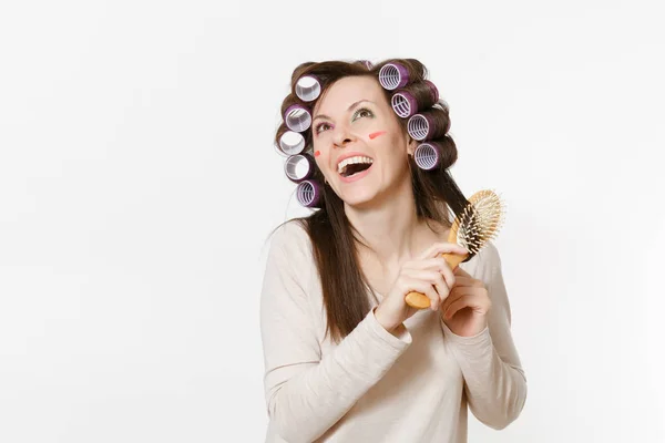 Young woman with curlers using combing with comb her hair isolated on white background. Crazy makeup with set facial decorative cosmetics. Beauty female fashion lifestyle concept. Area to copy space. — Stock Photo, Image