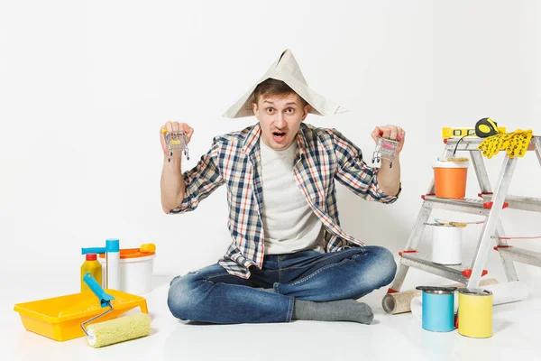 Jovem louco divertido em chapéu de jornal com supermercado empurrar carrinhos de supermercado para fazer compras. Instrumentos para renovação apartamento isolado em fundo branco. Ferramentas de pintura papel de parede. Reparação home concept . — Fotografia de Stock