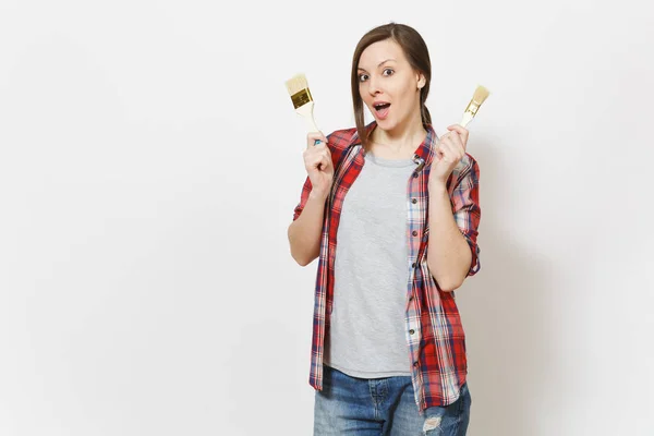 Junge schockierte schöne Frau in lässiger Kleidung mit Pinseln auf weißem Hintergrund. Instrumente, Zubehör für die Renovierung Wohnung Zimmer. Reparaturheimkonzept. Werbefläche. — Stockfoto