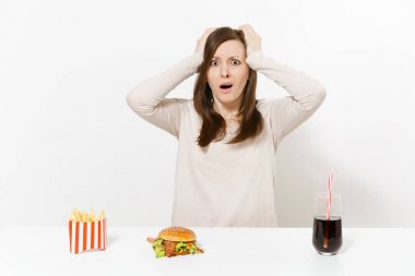 Şok kadın kafa burger patates kızartması kola cam şişe beyaz arka plan üzerinde izole masada ellerini koymak. Doğru beslenme veya Amerikan Klasik fast food. Alan kopya alanı ile reklam.