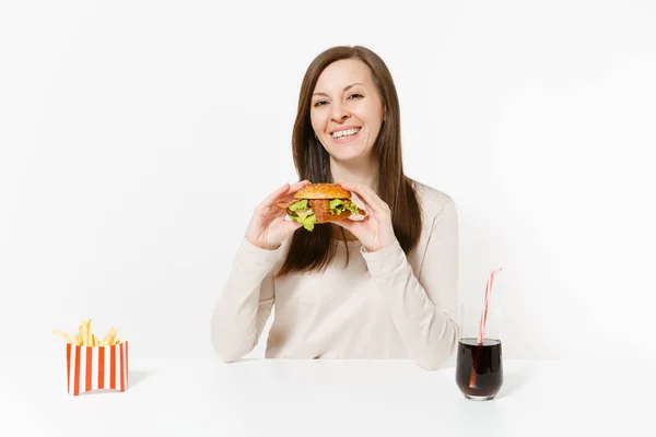 Mooie jonge vrouw zittend aan tafel met Hamburger, frietjes, in glazen fles cola geïsoleerd op een witte achtergrond. Goede voeding of Amerikaanse klassieke fastfood. Gebied met kopie ruimte reclame. — Stockfoto