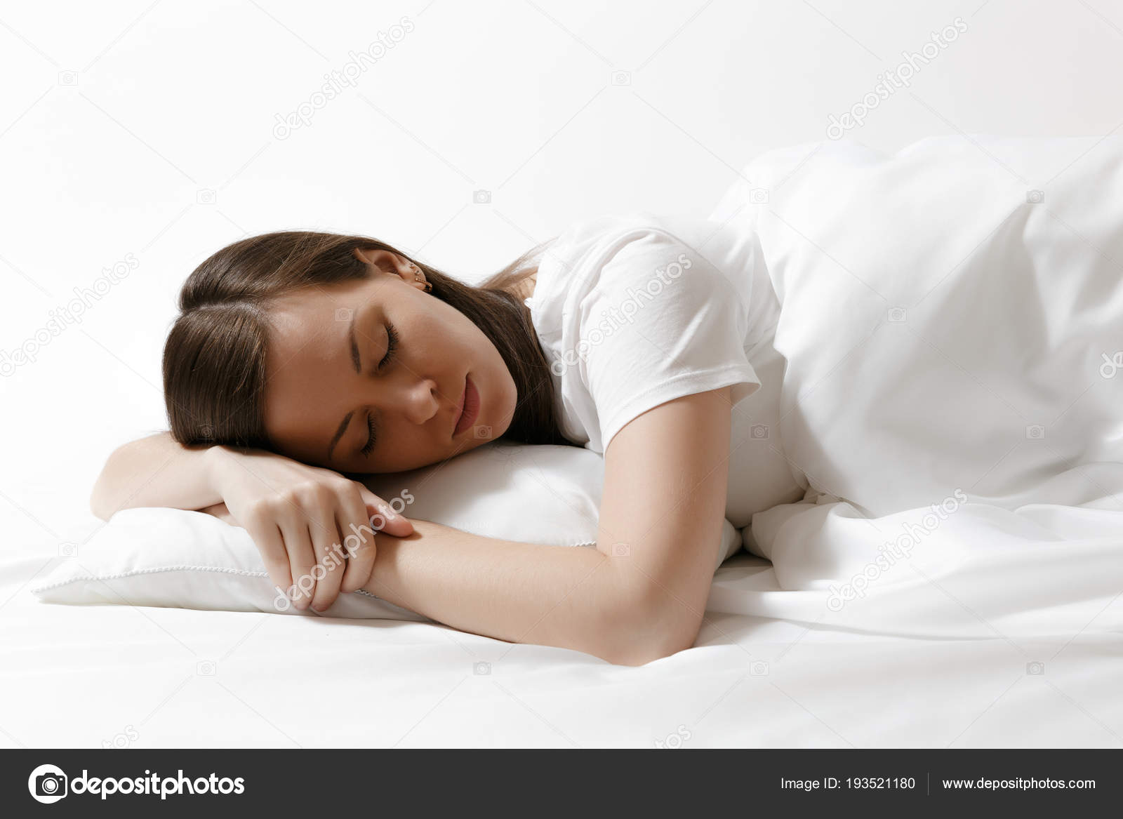 Calm Young Brunette Woman Lying In Bed With White Sheet