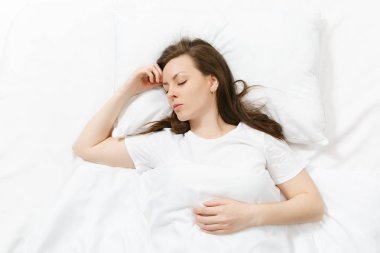 Üstten Görünüm mutlu sakin esmer genç kadının beyaz çarşaf, yastık, battaniye ile yatakta yalan. Vakit odasında uyuyan güzel kadın. Dinlenmek, iyi bir ruh hali kavramı sakin ol. Kopya alanı reklam için.