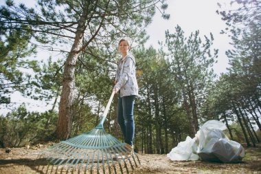 Temizlik çöp rak kullanarak rahat genç gülümseyen kadın giyim