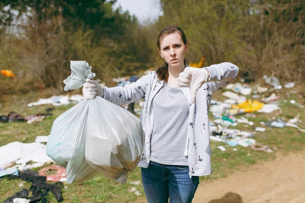 Joven mujer molesta en ropa casual limpieza sosteniendo bolsas de basura — Foto de Stock