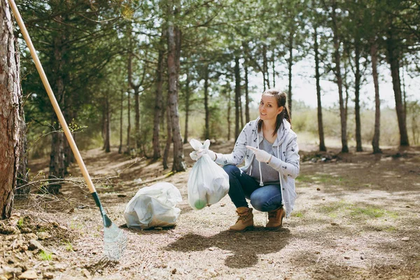 Young smiling woman cleaning rubbish and pointing index finger o
