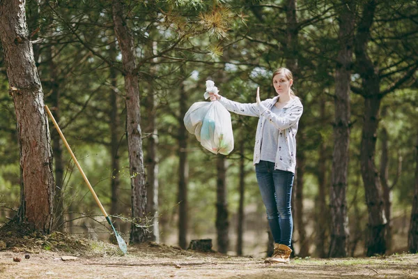 Mujer joven limpiando basura sosteniendo bolsas de basura y mostrando parada — Foto de Stock