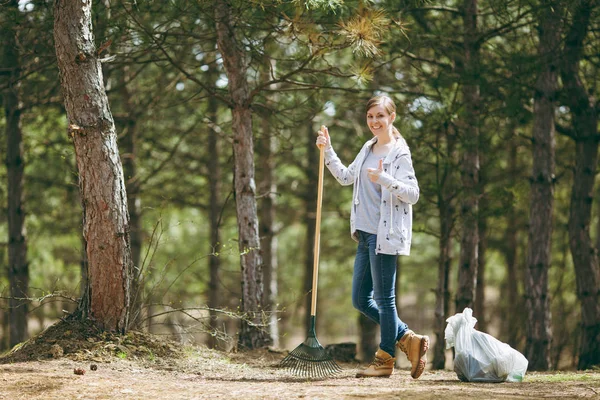 Joven mujer sonriente limpieza con rastrillo para la recolección de basura un — Foto de Stock