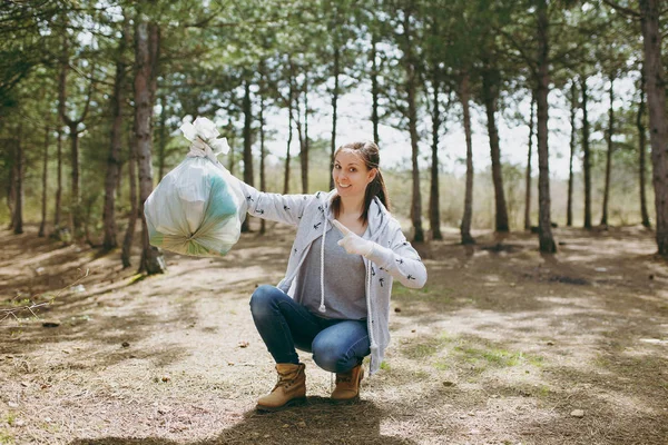 Joven mujer sonriente limpiando basura y señalando el dedo índice o — Foto de Stock