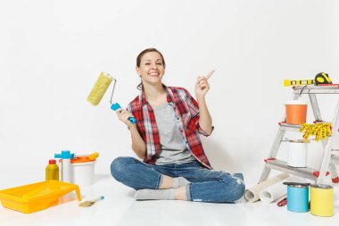 Rahat kıyafetler kat boya silindiri ile beyaz arka plan üzerinde izole yenileme daire için aygıtlar üzerinde oturan kadın. Duvar kağıdı, yapıştırma, boyama araçları için aksesuarlar. Onarım ev concept.