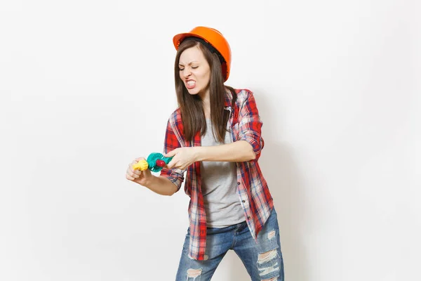 Роздратована божевільна жінка в повсякденному одязі та захисному будівництві помаранчевий шолом, що тримає іграшковий дриль ізольовано на білому тлі. Інструменти, інструменти для ремонту житлової кімнати. Ремонт домашньої концепції . — стокове фото