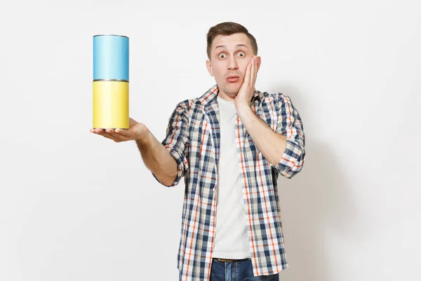 Joven impactado hombre guapo sosteniendo latas de pintura vacías con espacio para copiar y mantener las manos cerca de la cara aislada sobre fondo blanco. Instrumentos para la renovación de la habitación del apartamento. Reparación concepto hogar . — Foto de Stock