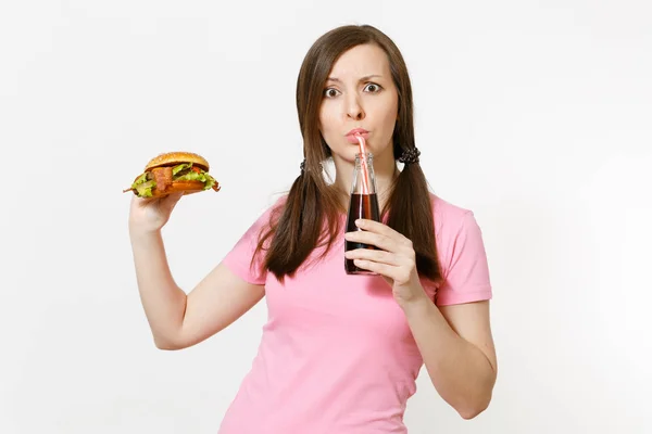 Schöne lustige junge Frau mit Schwanz steht und hält Burger, Cola in Glasflasche isoliert auf weißem Hintergrund. richtige Ernährung oder klassisches amerikanisches Fast Food. Werbefläche mit Kopierfläche. — Stockfoto
