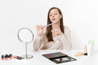 Çekici kadın tırnak düzeltme kullanarak tırnak ile beyaz arka plan üzerinde izole set yüz Dekoratif kozmetik makyaj uygulamak masada oturan, başarısız. Güzellik kadın moda yaşam tarzı kavramı.