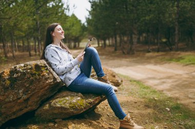 Rahat kıyafetler taş üzerine oturan genç rahatlatıcı gülümseyen kadın 