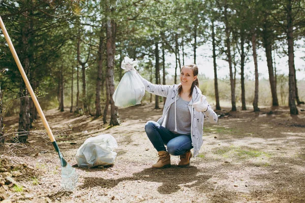 Joven mujer sonriente limpiando basura sosteniendo bolsas de basura mostrando — Foto de Stock