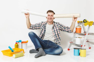 Rulo duvar kağıdı, beyaz arka plan üzerinde izole yenileme daire oda için aygıtlar ile katta oturan rahat kıyafetler gülümseyen adam. Aksesuarlar, boyama araçlarını yapıştırma. Onarım ev concept.