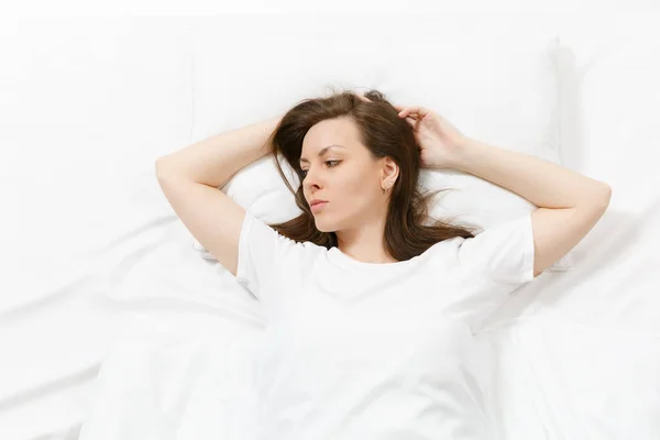 Top view of beautiful young woman lying in bed with white sheet, pillow, blanket. Calm pretty female looking aside, spending time in room. Rest, relax, good mood concept. Copy space for advertisement. — Stock Photo, Image