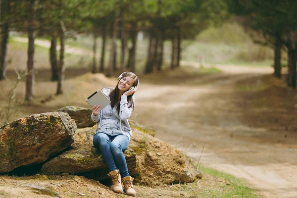 Jovem mulher sorridente relaxante em roupas casuais sentado em pedra — Fotografia de Stock