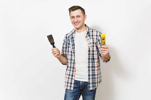 Joven hombre guapo sonriente en ropa casual sosteniendo cuchillo masilla y la construcción de burbuja nivel de espíritu aislado sobre fondo blanco. Instrumentos para la renovación de la habitación del apartamento. Reparación concepto hogar . — Foto de Stock