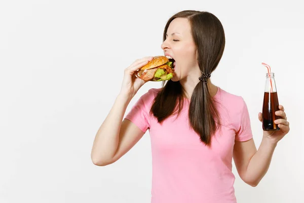 Hermosa mujer joven divertida con colas de pie y sosteniendo hamburguesa, cola en botella de vidrio aislado sobre fondo blanco. Nutrición adecuada o comida rápida clásica americana. Área de publicidad con espacio de copia . —  Fotos de Stock