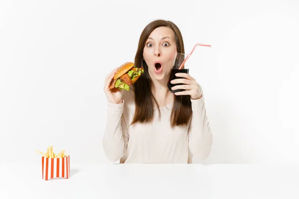 Beyaz arka plan üzerinde genç kadın masada oturan hamburger, patates kızartması, cam şişede cola ile izole mutlu eğlenceli. Doğru beslenme veya Amerikan Klasik fast food. Alan kopya alanı ile reklam. — Stok fotoğraf