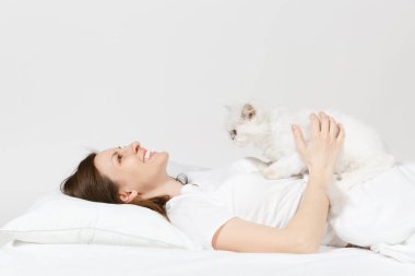Sakin genç kadın beyaz sevimli Farsça gümüş chinchilla kedi, sac, yastık, battaniye beyaz arka plan üzerinde ile yatakta yalan. Odada vakit geçirmek güzellik kadın. Dinlenmek, iyi bir ruh hali kavramı sakin ol. Kopya alanı