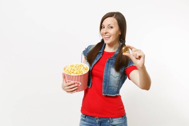 Film film izlerken, Kova patlamış mısır ve beyaz arka plan üzerinde izole bitcoin tutarak rahat kıyafetler içinde genç gülümseyen çekici esmer kadın portresi. Sinema kavramı duygular