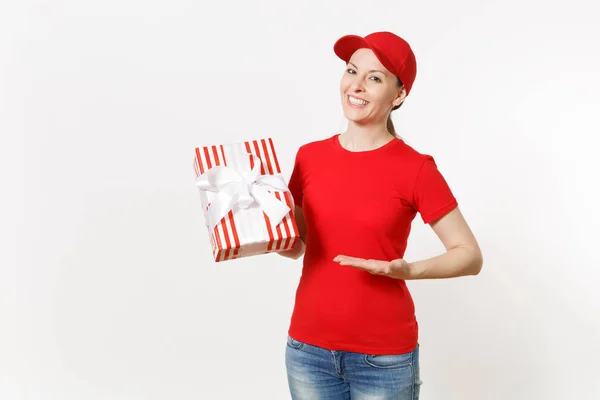 白い背景で隔離赤い制服を着た配達の女性 キャップ シャツ 女性宅配便または赤ストライプ ギフト ボックスを保持しているディーラーとして働いているジーンズを提示します 広告のためのスペースをコピーします — ストック写真