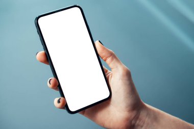 Parlak kurumsal ortamda, boş ekranlı, ince bezel cep telefonlu bir kadının el resmi - Görüntü