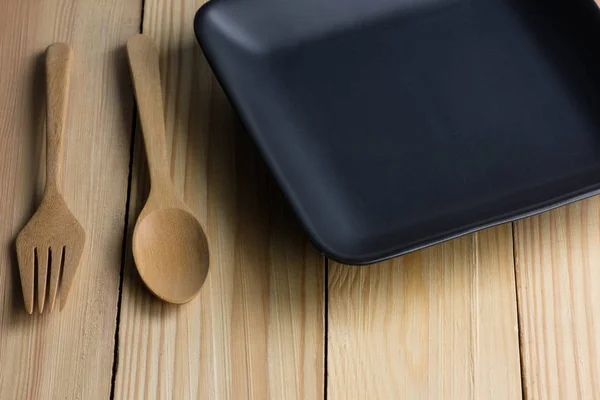 Κεραμική Μαύρη πλάκα και κουτάλι πάνω στο ξύλινο τραπέζι — Φωτογραφία Αρχείου