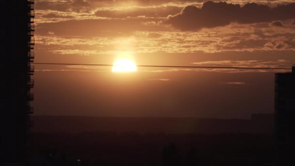 Puesta de sol fuera de la ciudad en las llanuras con rascacielos en primer plano con cielo nublado — Vídeos de Stock