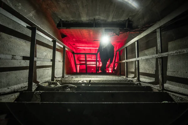 ランタンと赤の光を最後に男シルエットと地下通信のトンネル 地下に捨てられた階段 — ストック写真