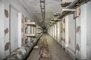 Boruları ve kabloları olan yeraltı beton kullanım tüneli.