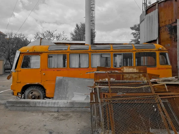 Old orange bus style of the 60s on scrap metal. Old fashioned abandoned bus.
