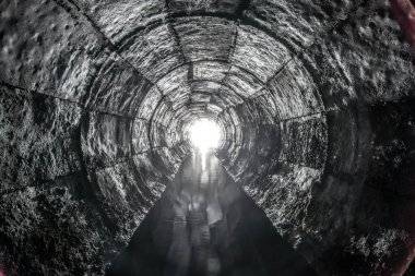 Yuvarlak drenaj beton tünel, biçimsel çalışmayla inşa edilmiş su. Sonunda ışık var. Tüpün içine gizlenmiş yeraltı nehri.