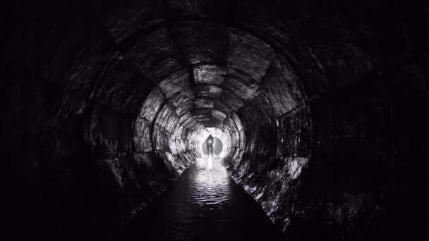 一个拿着灯笼的人走在地下的混凝土集雨器里 — 图库视频影像