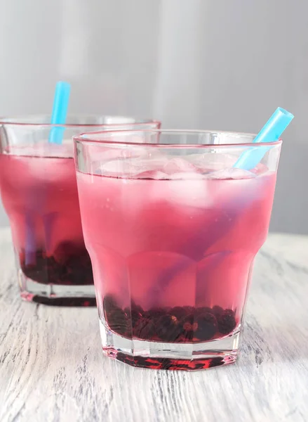 Pink berry chilled drink. Drink of the currant in a glass on a wooden table.