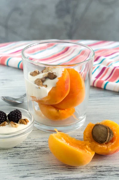 Dessert with peaches and cream . Peach in the glass with sweet cream and nuts.