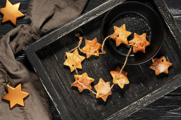 A star cookie on an old black wooden table and a black cup. The top view.