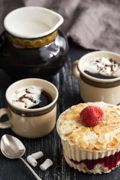 Dessert with almond cream and strawberries. Coffee with marshmallows. Rustic background.