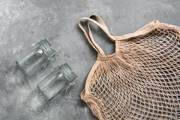 Zero waste. Cotton mesh bag and glass jars on a dark background, top view, flat lay, copy space.