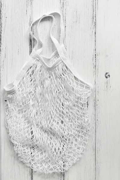 Zero waste. White cotton mesh bag on a white rustic wooden board background. Top view, flat lay, copy space.