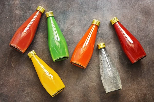 Assorted various colored juice in bottle on a dark background. Top view, flat lay. Juice - dragon fruit, orange, kiwi, carrot, guava and tomato