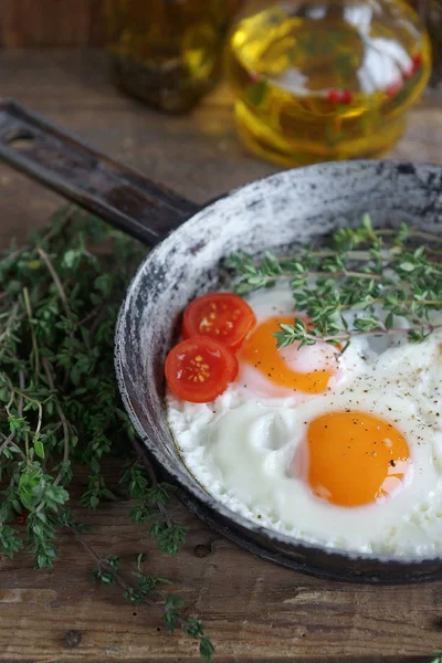 Fried eggs in old pan with tomatoes — Stock Photo, Image