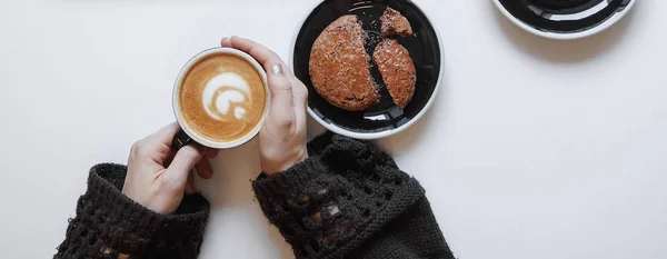 Cup of coffee in hands and cookie